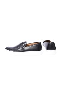 Scarpe nere in pelle slip-on con punta arrotondata, dotate di suola in gomma bianca e dettagli di cucitura sottili sulla parte superiore.