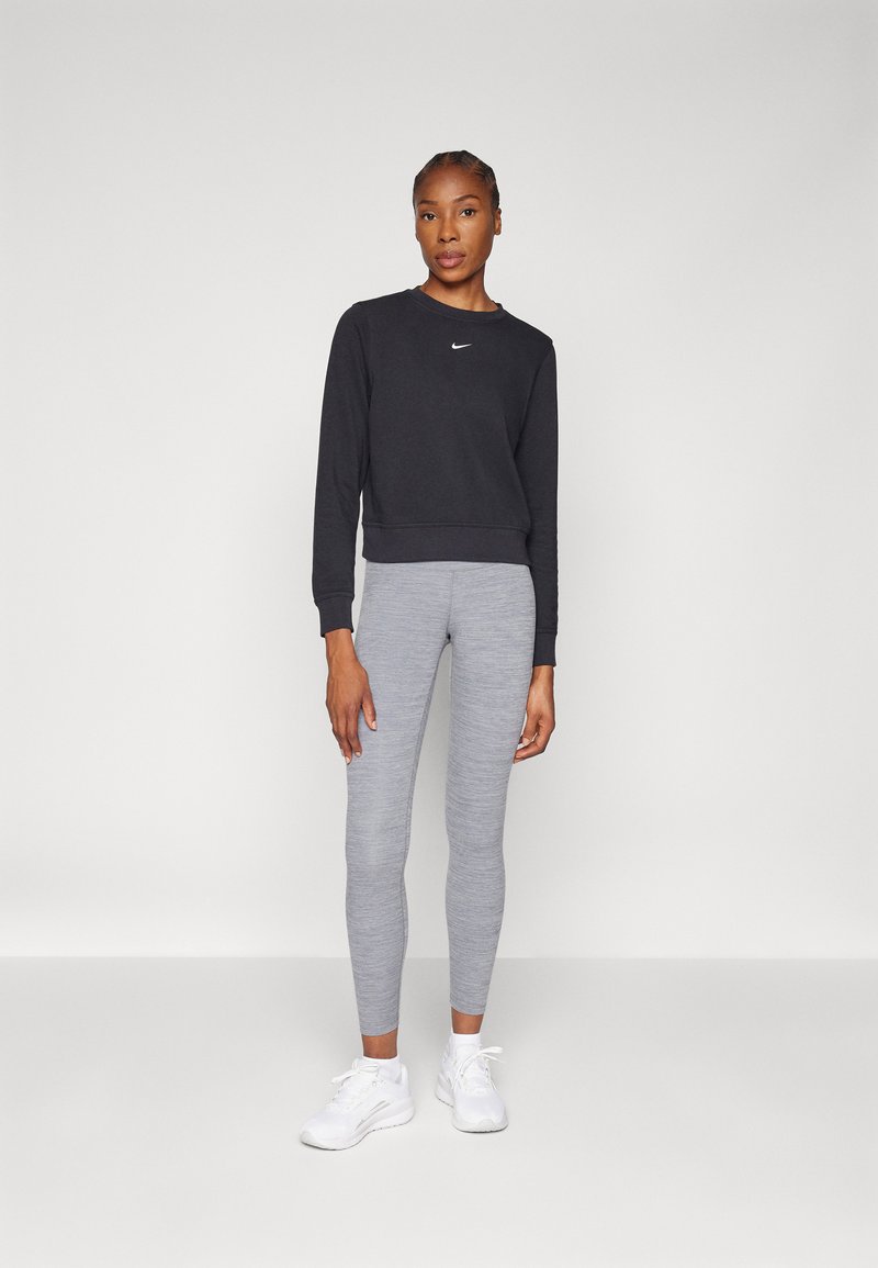 Svart sweatshirt med rund hals och logo, grå leggings och vita sportskor. Slät tygkvalitet, figurnära design och ribbade muddar.