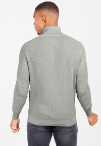 Pulover tricotat cu nervuri de culoare gri deschis, cu guler înalt și manșete ajustate, având un design din spate fără cusături și un material texturat.