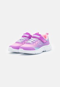 Baskets de sport violettes et roses avec une tige en maille texturée, des sangles ajustables et une semelle en caoutchouc blanche avec un talon proéminent.