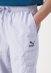 Licht paarse shorts van zachte stof, met een elastische tailleband, zijzakken en een zwart Puma-logo op de linker bovenbeen.