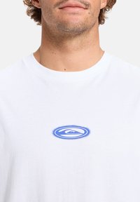 White cotton t-shirt featuring a blue circle logo with a wave design at the center. Classic crew neck and short sleeves.