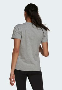 Szara koszulka z krótkim rękawem, wykonana z miękkiego materiału bawełnianego, z okrągłym dekoltem. Tył jest gładki, z lekko dopasowanym krojem.