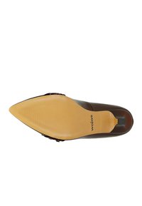 Scarpa con tacco alto marrone, punta affusolata, tomaia in pelle liscia e suola in gomma beige caratterizzata da una texture rigata e logo del brand.