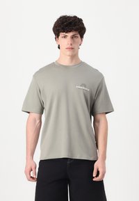 Olivengrøn bomulds t-shirt med korte ærmer og rund halsudskæring, der har et lille "Athletic Club" logo på venstre brystområde.