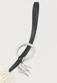 Črni usnjeni trak s šivi, pritrjen na srebrn kovinski obroč z vgraviranim napisom "KARL LAGERFELD" in majhno srebrno značko s podpisom.