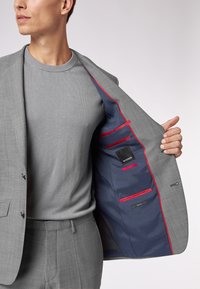 Grau Anzugjacke mit feiner Textur und Revers, ausgestattet mit einem blauen Innenfutter, das mit roten Akzenten abgesetzt ist, und mehreren Innentaschen.