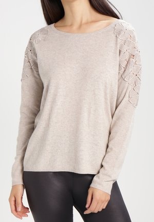Pull en beige à manches longues en maille douce, avec des détails en dentelle florale sur les épaules et une coupe décontractée.