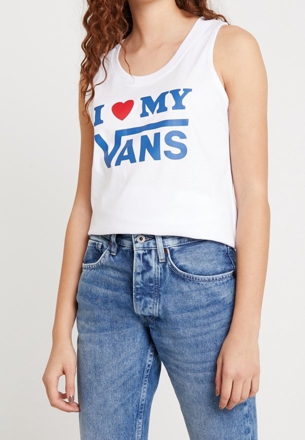 Crop top blanc sans manches avec un graphisme "J ❤️ MES VANS" en bleu et rouge. Associé à un jean taille haute bleu clair.