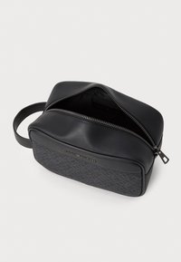 Trousse de toilette noire avec un panneau texturé à motif géométrique, fermeture éclair et poignée latérale pour un transport facile.