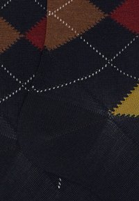 Tessuto lavorato a maglia con sfondo blu navy e motivo a rombi in marrone, rosso e giallo. Cuciture bianche delineano i rombi.