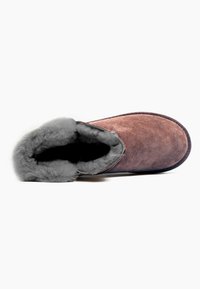 Pantofole in suede marrone con morbida fodera in finta pelliccia grigia lungo l'apertura, suola piatta e punta arrotondata. Design semplice e minimalista.