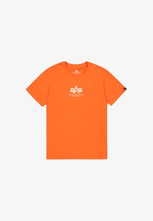 T-shirt en coton orange avec un col rond. Présente un logo graphique blanc sur la poitrine et une petite étiquette noire sur la manche gauche.