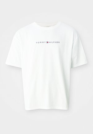 Balta īsroku T-krekls ar apaļu izgriezumu un tekstu "Tommy Hilfiger" un logotipu, kas centrēti uz krūtīm.