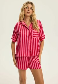 Różowy i czerwony, w paski, jedwabny zestaw piżamowy składający się z koszuli z krótkim rękawem zapinanej na guziki z kieszenią oraz pasujących szortów. Gładka tekstura, luźny krój.