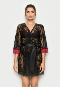 Černý krajkový župan s červeným krajkovým lemem na rukávech. Obsahuje černý saténový pásek a průhledný design, který zvýrazňuje složité květinové vzory.