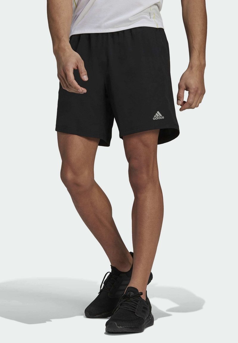Zwarte sportshorts met een elastische tailleband en het grijze Adidas-logo aan de linkerbenedenkant. Lichtgewicht, gladde stof.