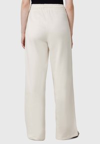 Cremfarbene weite Hosen aus weichem Stoff, mit elastischem Bund und dezenten Seitenschlitzen am Saum.