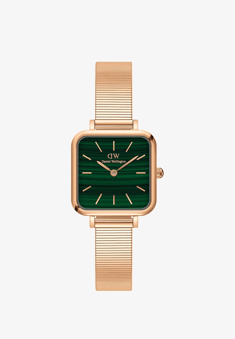 Kvadrāta formas rokas pulkstenis ar zaļu svītrotu ciparnīcu, rozā zelta korpusu un milāniešu acu siksnu. Vienkārši stundu rādītāji un rokas, minimālisma dizains.