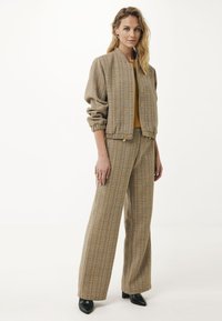 Kamizelka bomber w kratkę z elastycznymi mankietami, w zestawie z dopasowanymi spodniami z szerokimi nogawkami. Oba elementy mają subtelne tekstury i zapięcie na guzik.