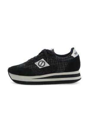 Black and grey low-top sneaker with thick white and black striped sole, black laces, and a round logo patch on the side.