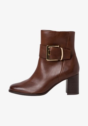 Hnědá kožená kotníková bota se širokým páskem a zlatou přezkou, s blokovým podpatkem a hladkým, lesklým texturem.