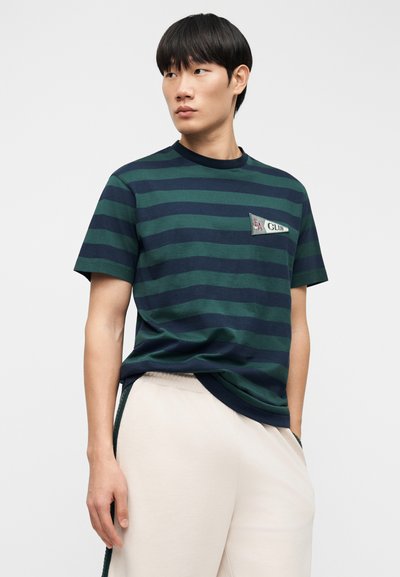 Ριγέ κοντομάνικη μπλούζα σε σκούρο πράσινο και ναυτικό μπλε, με στρογγυλή λαιμόκοψη και τσέπη με κεντημένο λογότυπο "EA Club".