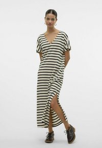 Robe maxi rayée en crème et noir avec des manches courtes bouffantes, un décolleté en V et des fentes latérales. Associ ée à des chaussures à lacets sombres.