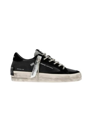 Sneaker nera bassa con suola bianca consumata, lacci con motivo e testo "Crime London" sul lato e sull’etichetta appesa.