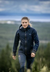 Navy vettimäntävä takki, jossa on huppu, vetoketjullinen etuosa ja säädettävät hihansuut. Yhdistetty yhteensopiviin tummansinihin housuihin, joissa on taskut ja vahvistetut polvet.