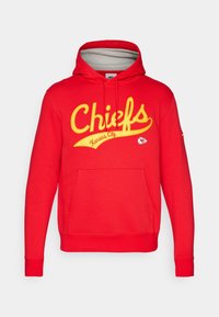 Raudona striukė su geltonu tekstu "Chiefs" ir "Kansas City" parašytu kursyvu. Yra priekinė kišenė, reguliuojama kapuca ir raibuotos rankovės.