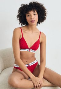 Crvena bralette i odgovarajući bikini set s malim crnim uzorcima srca. Elastične trake s "TOMMY HILFIGER" brandom. Mekana, rastezljiva tkanina.
