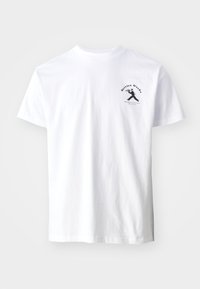 White cotton t-shirt featuring a black graphic print of a figure and text "Service Works" on the left chest area. Short sleeves, crew neckline.