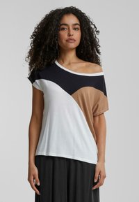 T-shirt à manches courtes avec un design divisé en noir, blanc et marron clair. Tissu doux avec une coupe décontractée et un décolleté épaule dénudée.