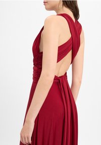 Rotes Kleid mit tiefem Rückenausschnitt, gerafftem Oberteil und drapiertem Stoff. Verfügt über breite Träger und eine Bindegürtel-Detailungen an der Taille. Glatte Textur.
