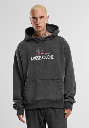 Kolkgrå hoodie med kängurufickor, ribbade ärmslut och en framsidan grafisk textdesign i rosa och vitt som säger: "Jag kommer att vara din AMUSE-BOUCHE."