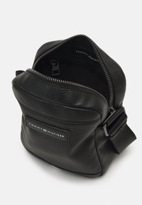 Borsa a spalla in pelle nera texturizzata con apertura con zip, caratterizzata da una tampografia rettangolare e una tracolla regolabile.