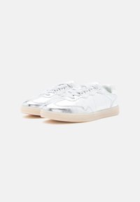 Sneakers argento metallizzato con una texture liscia, caratterizzate da un profilo basso, punta tonda e suola in gomma chiara. Lacci integrati nel design.