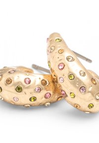 Pendientes de aro en tono dorado con piedras de strass rosas, verdes y ámbar sobre una superficie texturizada martillada, mostrados sobre un fondo blanco.