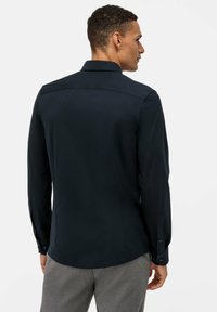 Camicia a maniche lunghe blu navy con colletto classico, dettaglio di yoke posteriore e polsini con bottoni. Tessuto morbido, vestibilità su misura.
