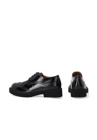 Schwarze Lackleder-Schnürschuhe mit glatter Oberfläche, Flügelspitze und einer dicken schwarzen Gummisohle. Minimalistisches Design.