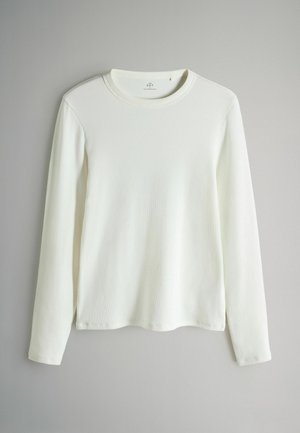 Garšs piedurkņu kreklis ar apaļu kakla izgriezumu, izgatavots no baltas ribotas auduma. Iezīmē taisnu griezumu ar sānu izgriezumiem apakšmalā un maigu, teksturētu virsmu.