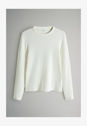 Długi rękaw, okrągły dekolt w białym, ribbowanym materiałem. Posiada prosty krój z bocznymi rozcięciami u dołu oraz miękką, teksturowaną powierzchnię.