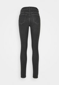 Jeans ajustados de mezclilla gris oscuro, con cintura alta, bolsillos traseros y una textura suave. Las piernas se estrechan hasta el tobillo.