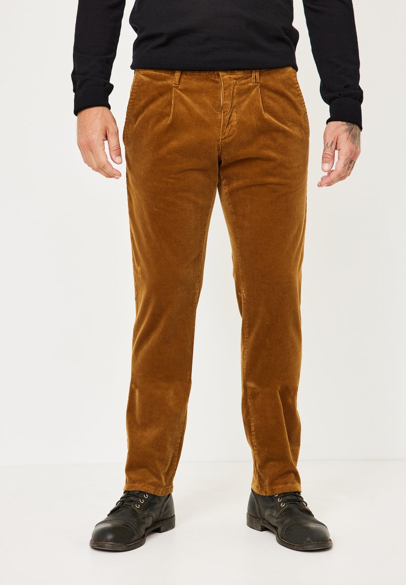 Braune Cordhosen mit einer gerippten Textur, gerades Bein Design, seitlichen Taschen und getragen mit schwarzen Lederschuhen.