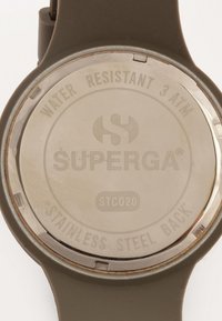 Reloj con correa de silicona verde y fondo de acero inoxidable. Los detalles grabados incluyen "RESISTENTE AL AGUA 3 ATM" y "SUPERGA® STC020."