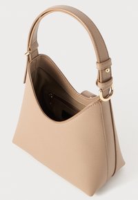 Beige Handtasche aus strukturiertem Material, mit einem gebogenen Oberteil, einem verstellbaren Tragegurt und einer kleinen Innentaschen mit Reißverschluss. Goldene Hardware-Akzente.