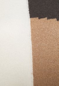 Pull en tricot avec des rayures verticales en crème, marron et gris foncé. Texture douce avec un motif de tricot uniforme et des bords nets.