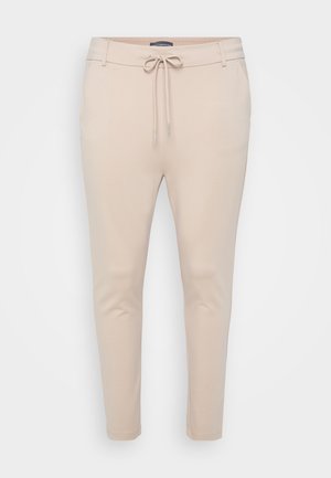 Beige lett joggebukser med snøring i midjen og to sidelommer. Glatt tekstur, avsmalnende ben og minimal sømdetaljering.