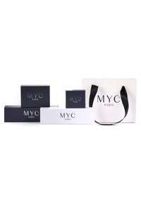 Scatole di prodotto nere e bianche di diverse dimensioni, con il logo "MYC PARIS", accompagnate da una borsa da shopping bianca con manici neri.